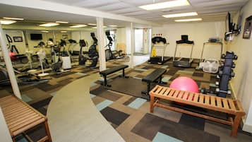 A gym with exercise equipment, a mirrored wall, and a patterned carpet.