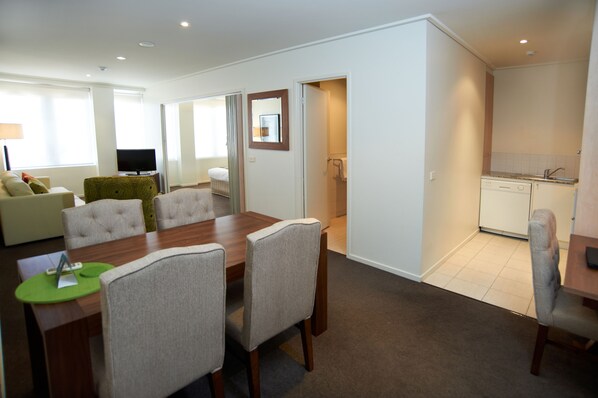 A modern hotel room with a dining area, a living room, and a kitchenette.