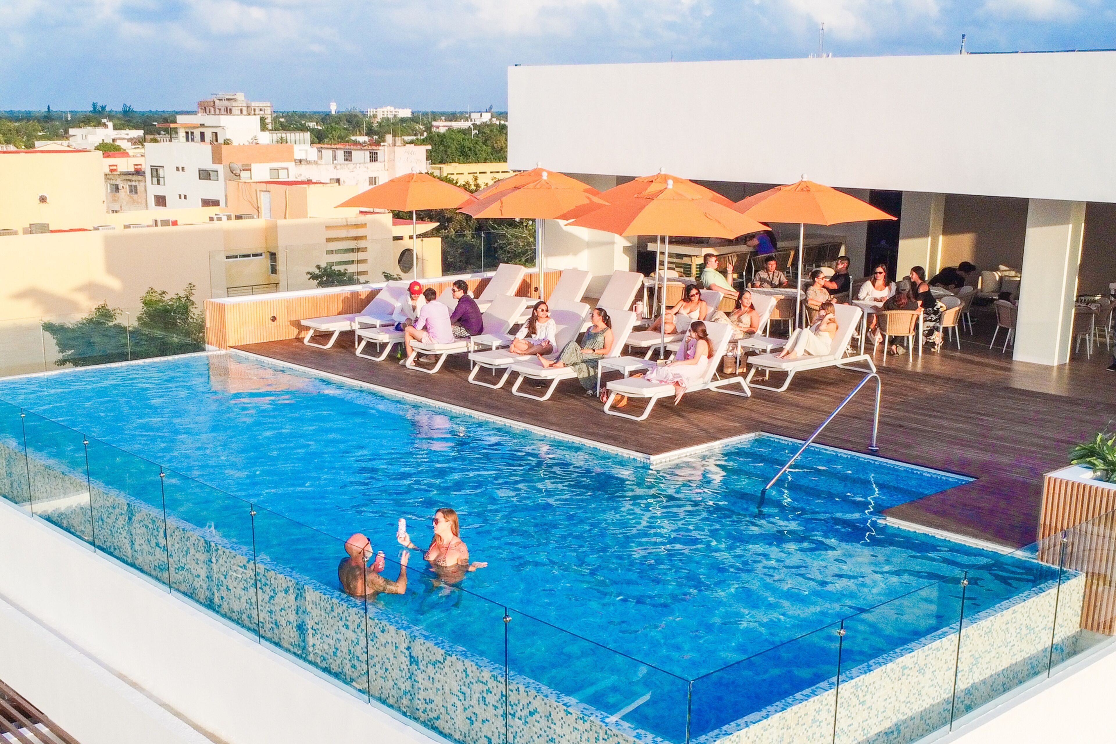 A rooftop pool with lounge chairs and umbrellas, surrounded by buildings.