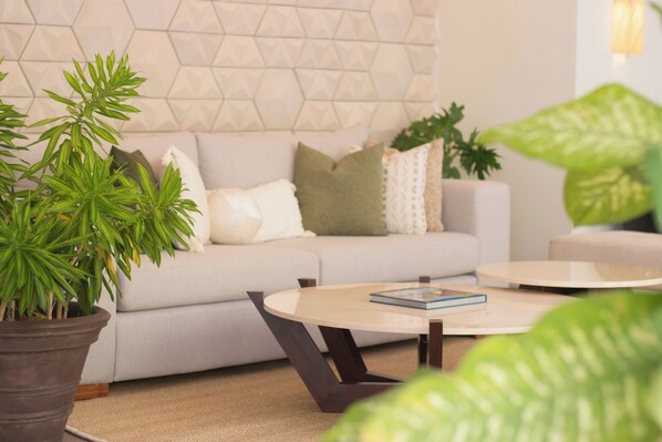 Una sala de estar moderna con sofá, mesa de centro y plantas en macetas.