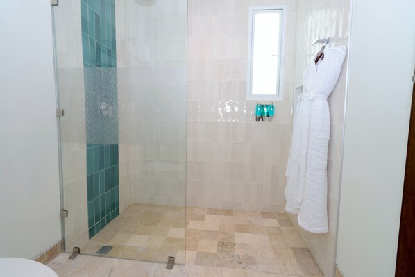 A bathroom with a glass-enclosed shower, tiled walls, a window, and a towel rack with white towels. - Hotel Casa Bahía Cozumel - Adults Only (Cozumel)
