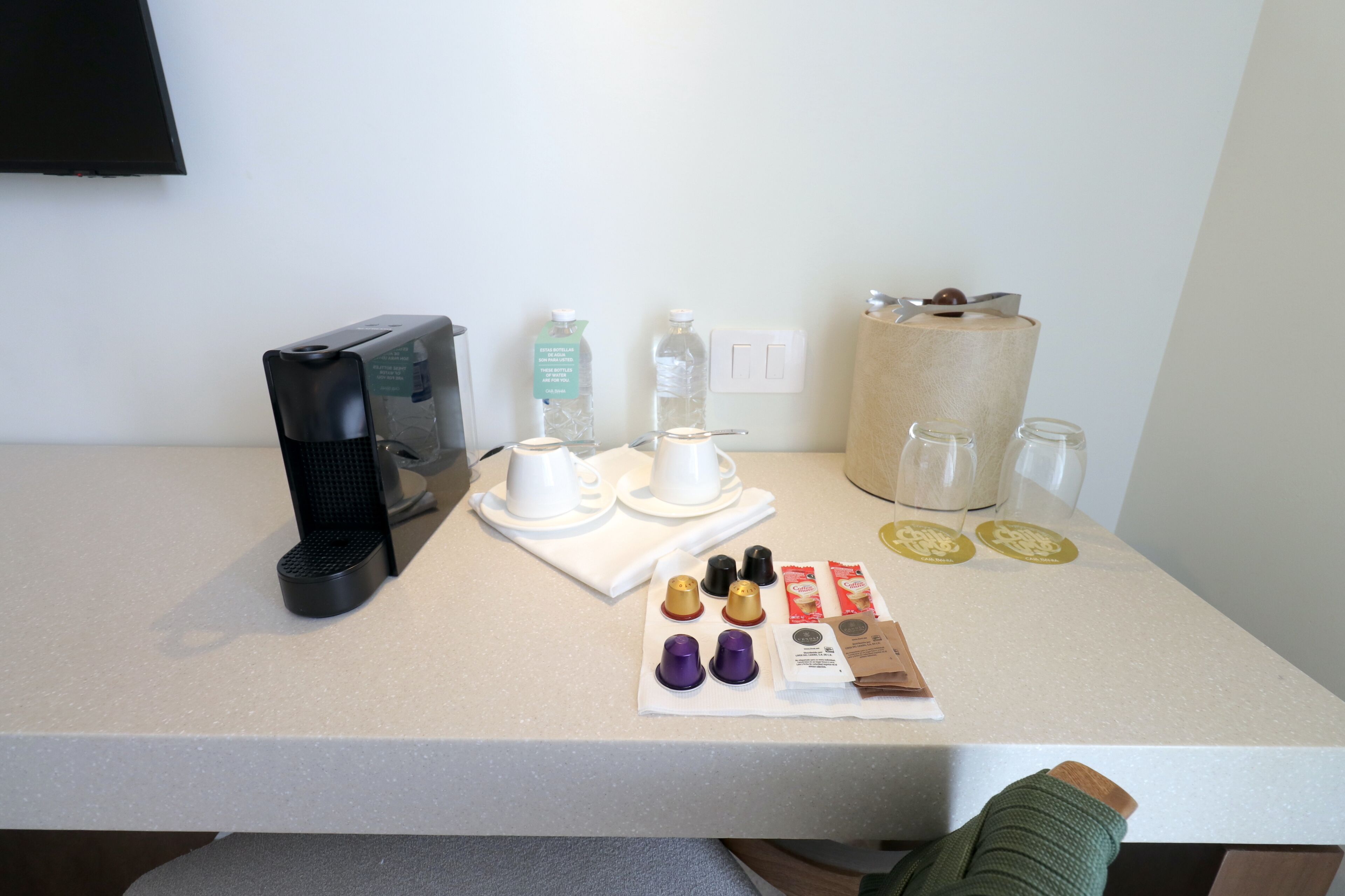 A coffee station with a coffee maker, cups, and coffee pods on a countertop.