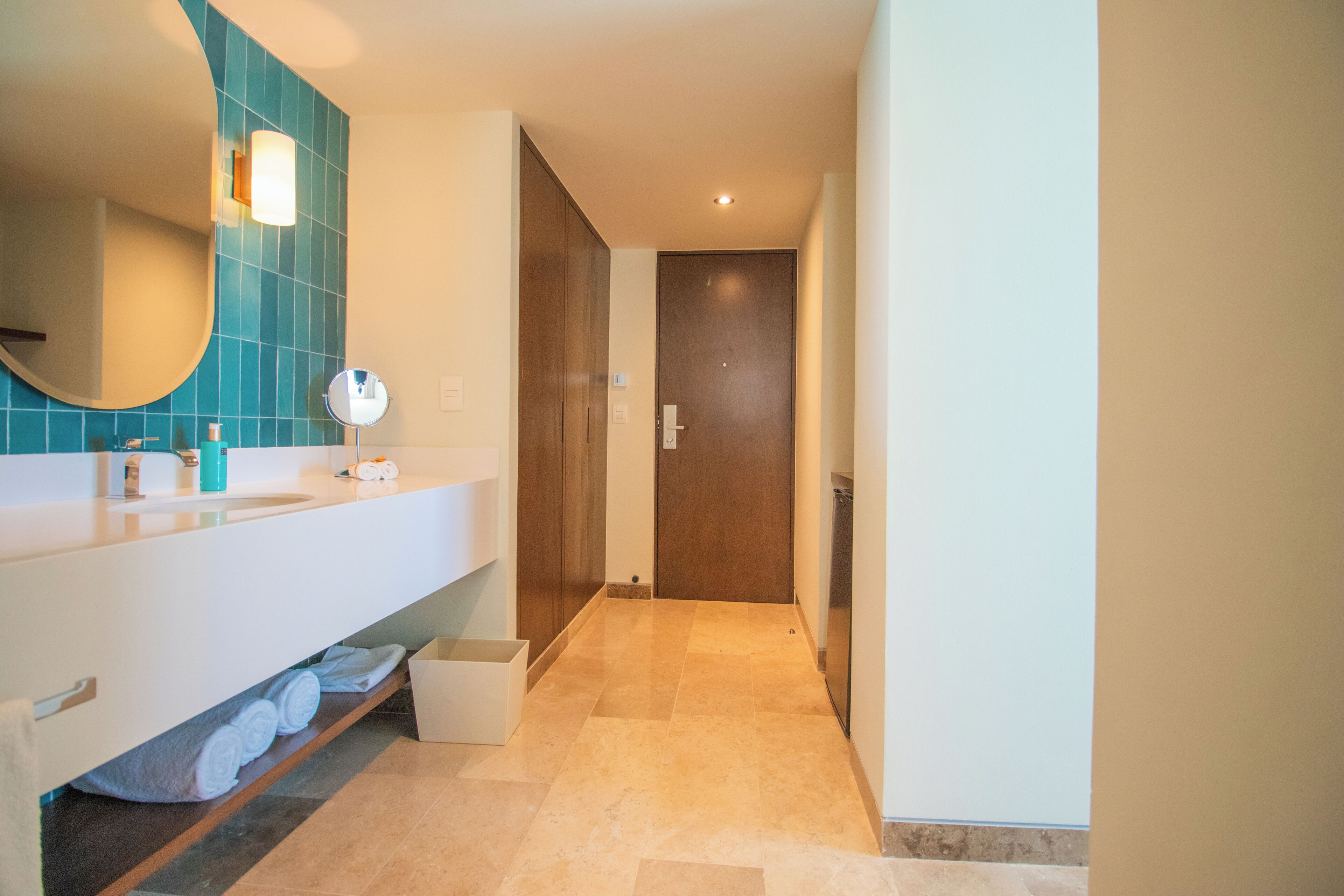 A modern bathroom with a white vanity, a large mirror, and a blue-tiled wall.