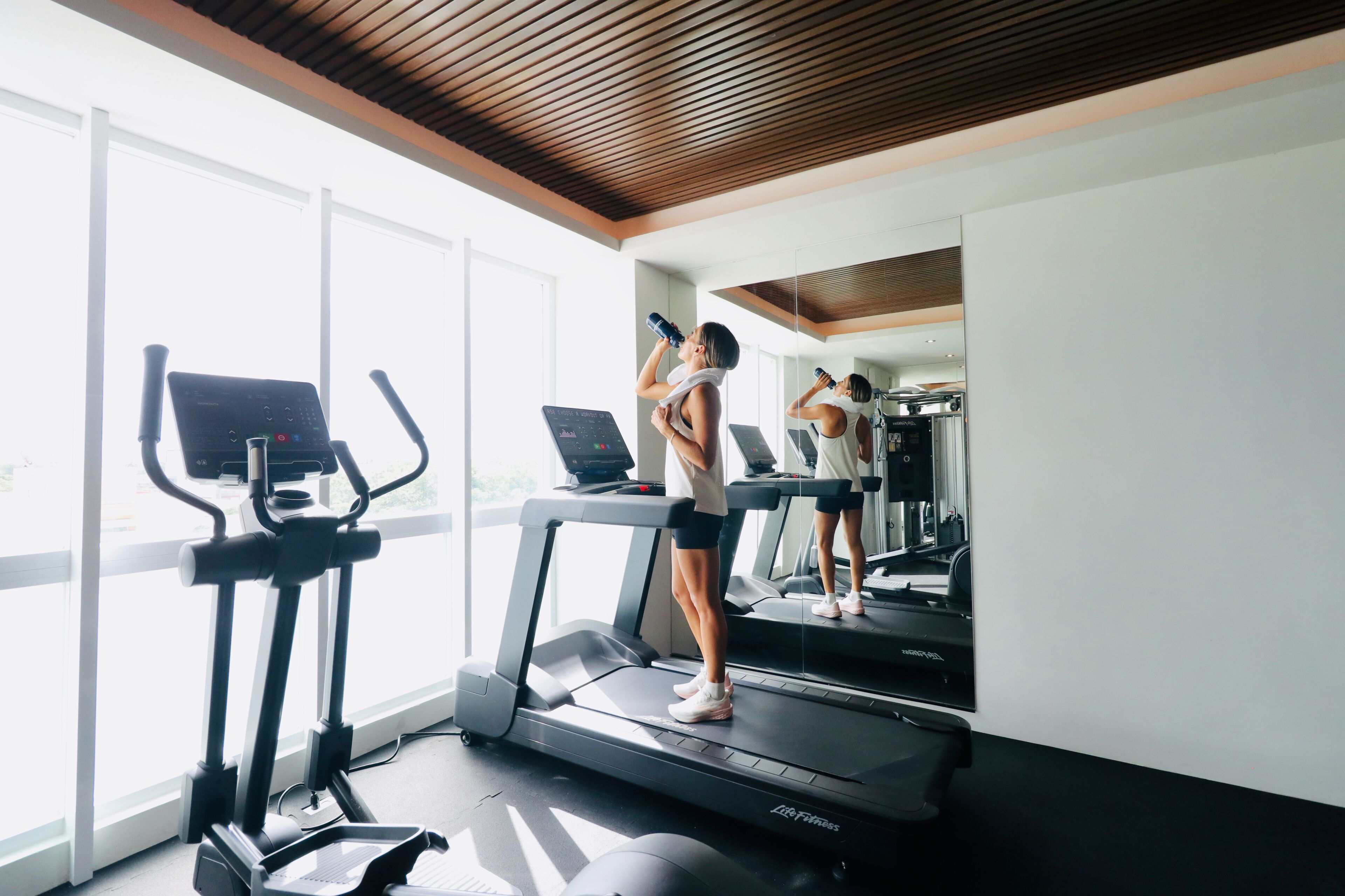 A gym with treadmills, an elliptical, and a mirror reflecting the space.
