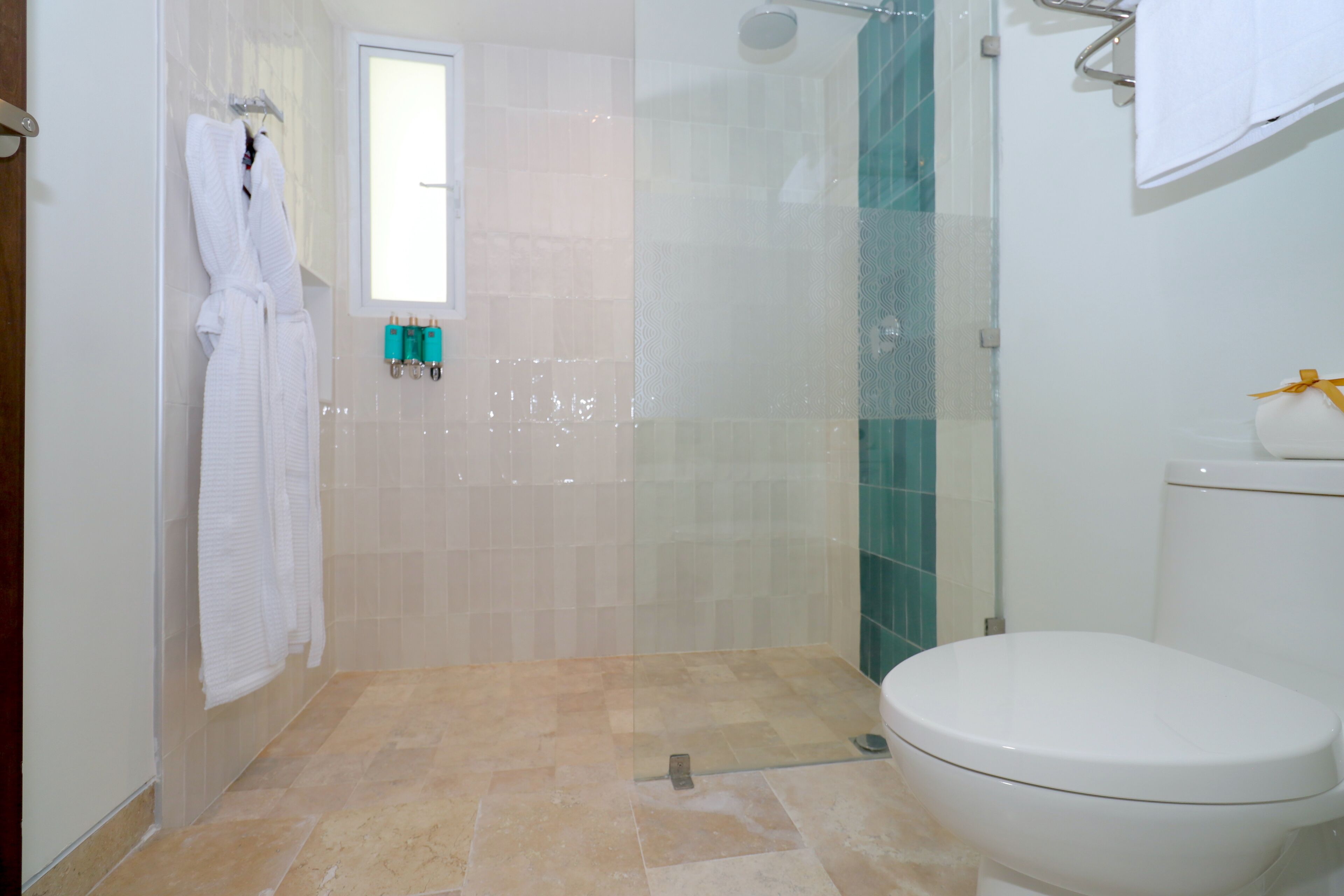 A bathroom with a shower, toilet, and a window.