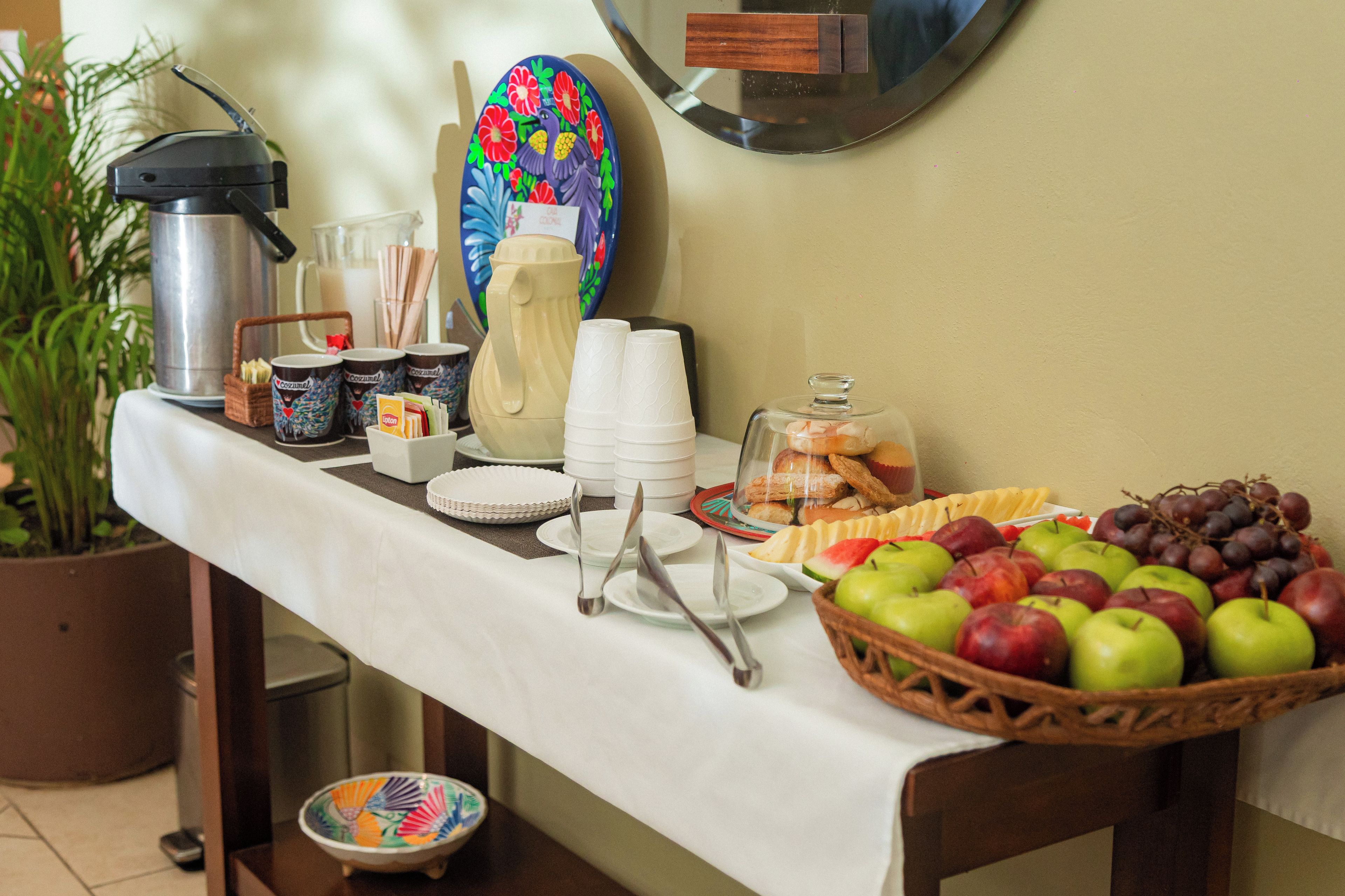 A breakfast buffet setup with various food items, utensils, and a coffee machine.