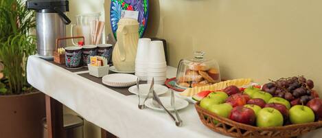 A breakfast buffet setup with various food items, utensils, and a coffee machine.