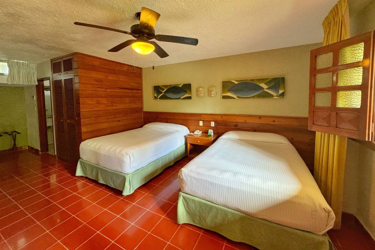 A room with two beds, a ceiling fan, and a wooden headboard.