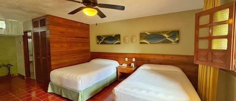 A room with two beds, a ceiling fan, and a wooden headboard.
