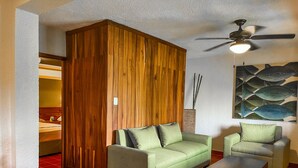 A living room with a wooden wardrobe, a green sofa, a matching armchair, and a wooden coffee table. - Hotel Casa Colonial Cozumel (Cozumel)