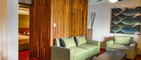 A living room with a wooden wardrobe, a green sofa, a matching armchair, and a wooden coffee table.