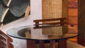 A round glass table with a wooden chair in front. - Hotel Casa Colonial Cozumel (Cozumel)