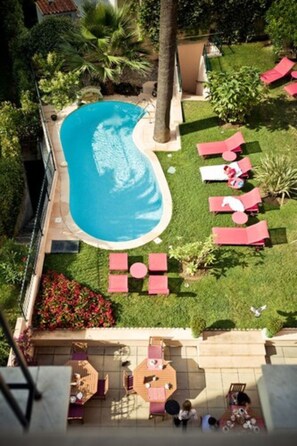 An aerial view of a pool area with lounge chairs, a dining area, and a small garden with flowers. - Sun Riviera (Cannes)