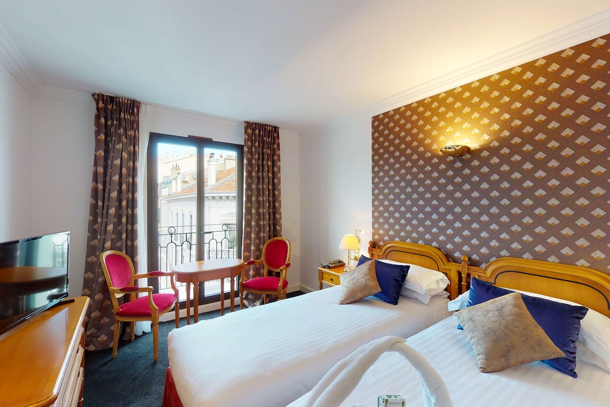 A hotel room with a bed, bedside table, lamp, and a chair.