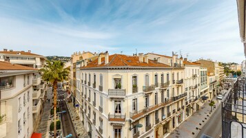 Un edificio de varios pisos con balcones, vista a la calle y cielo despejado.