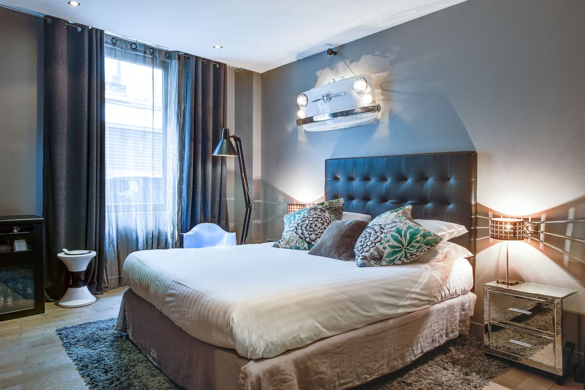 A modern bedroom with a large bed, a headboard, and a wall-mounted light fixture.