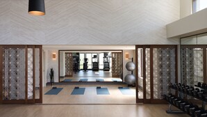 A spacious gym with exercise mats, dumbbells, and a mirrored wall reflecting the interior. - Austin Marriott South (Austin)