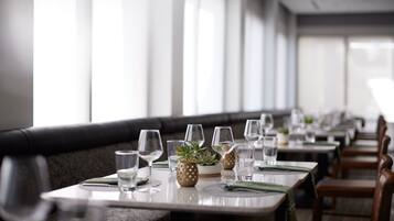 A restaurant with long tables set for dining, each with a water glass, a small plant, and a napkin.
