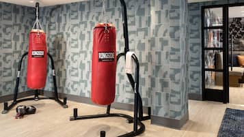 Un gimnasio en casa con dos sacos de boxeo rojos, piso de madera y pared con diseño.