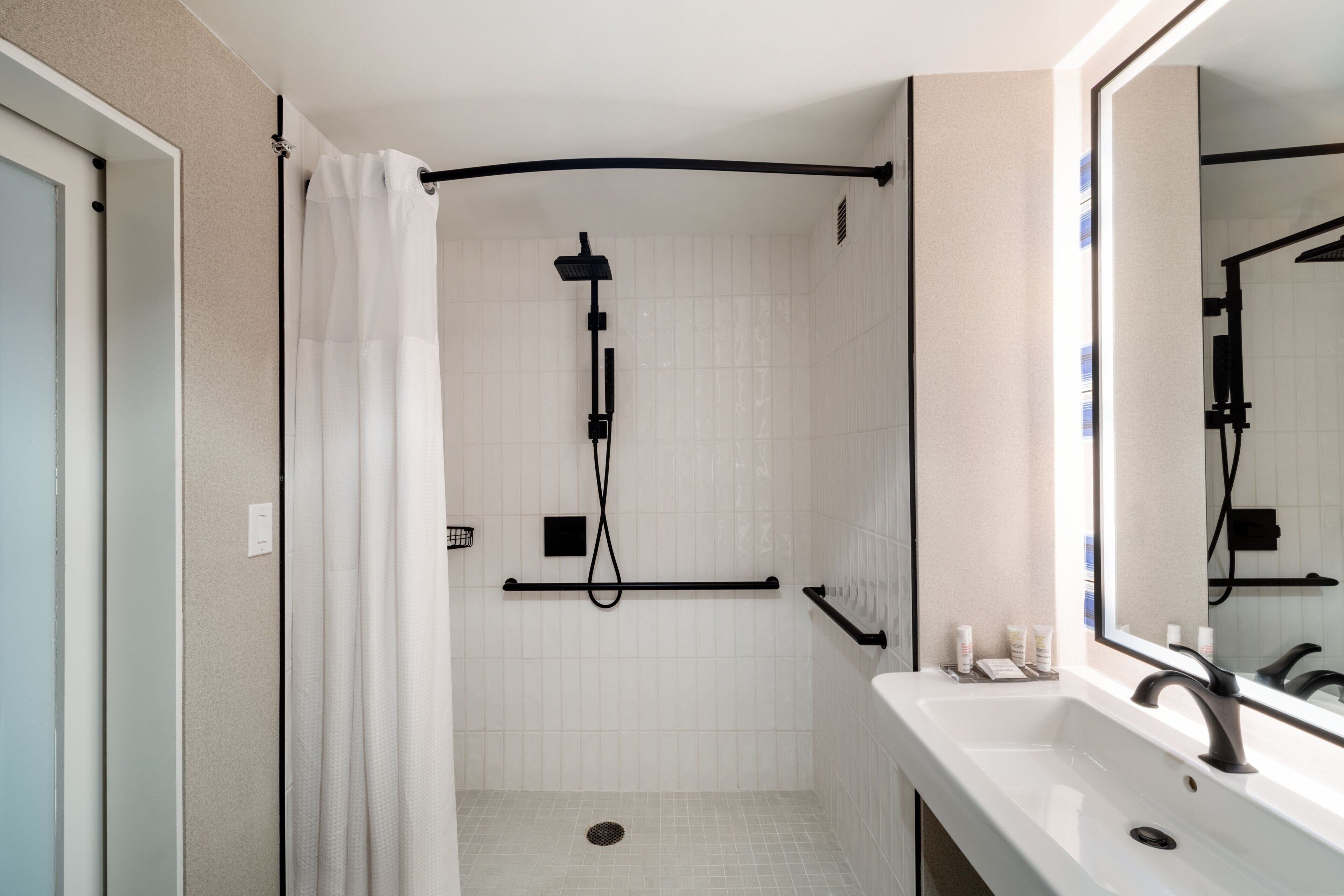 A modern bathroom with a shower, a sink, and a mirror.
