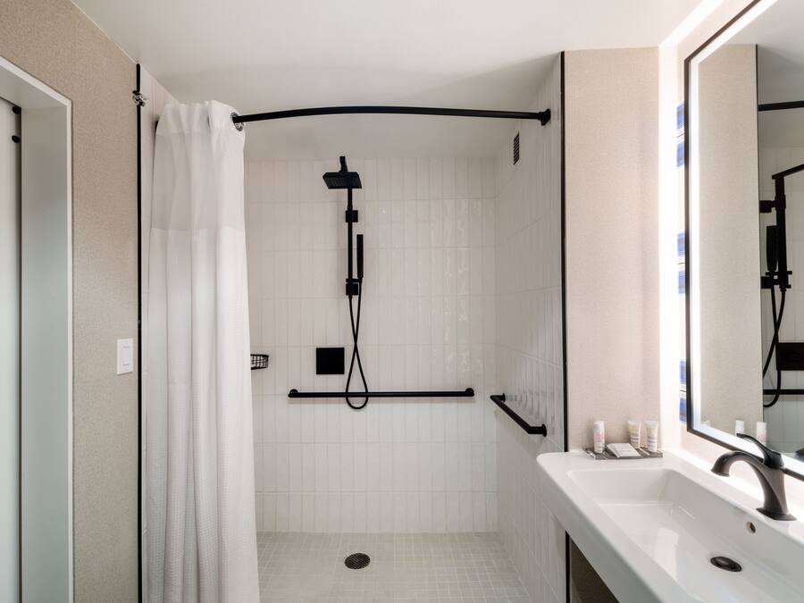 A modern bathroom with a shower, a sink, and a mirror.