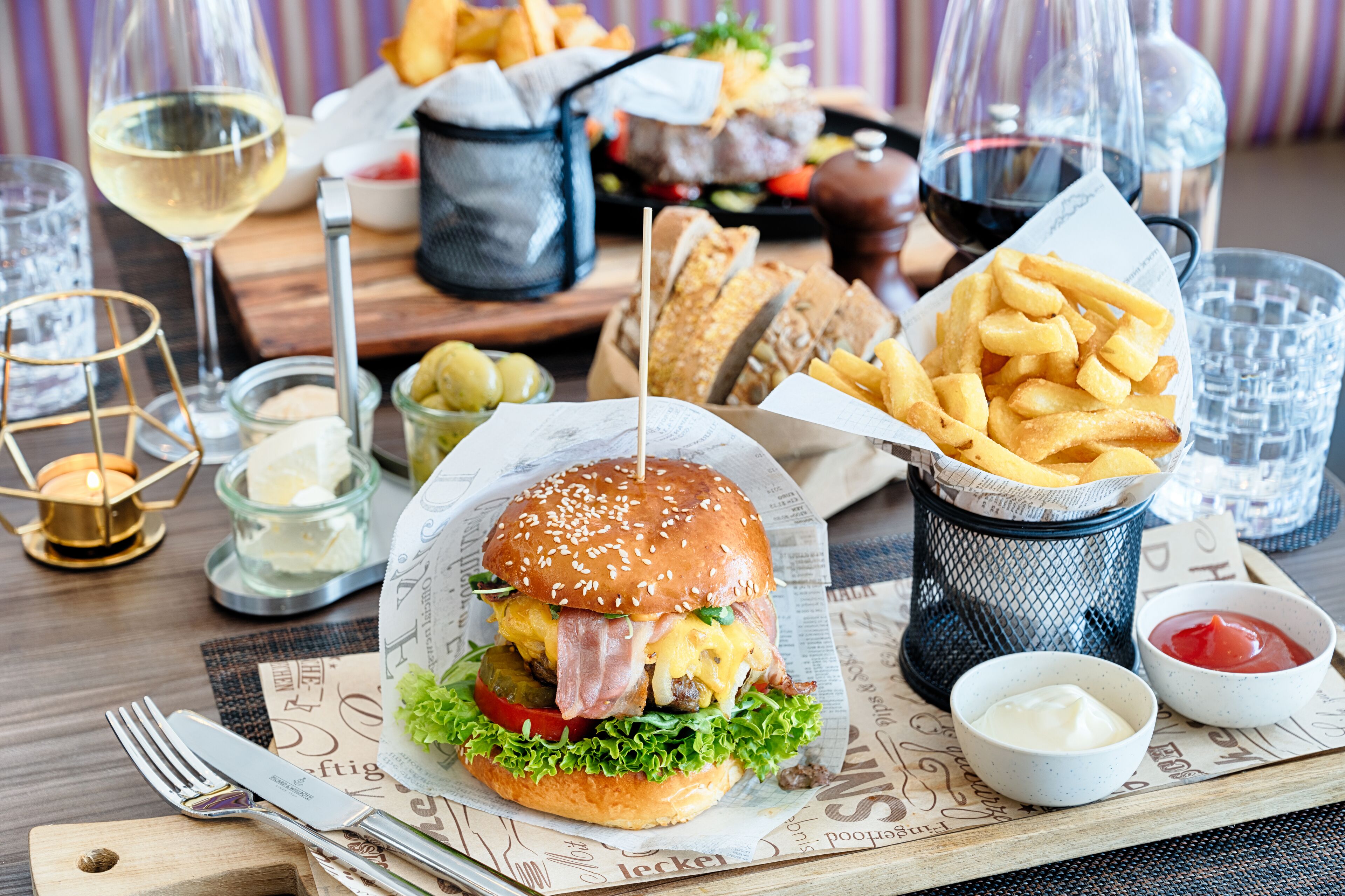 Ein Essen mit einem Burger, Pommes und Getränken auf einem Holztisch.