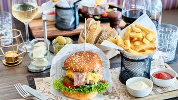 Ein Essen mit einem Burger, Pommes und Getränken auf einem Holztisch.