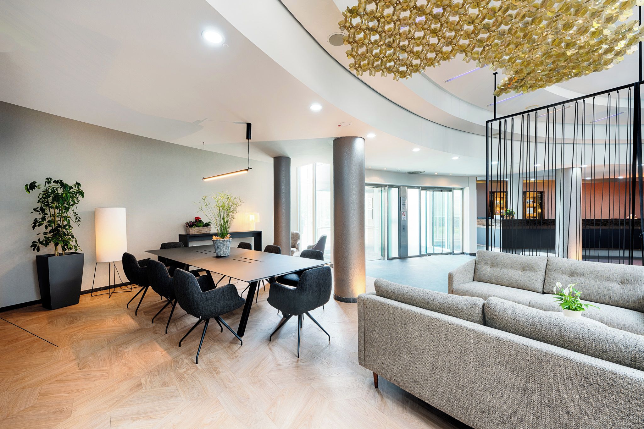A modern interior with a dining area, sofas, and a unique ceiling design.