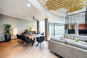 A modern interior with a dining area, sofas, and a unique ceiling design.