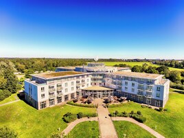 A modern hotel with a central courtyard, multiple balconies, and a clear view of the surrounding landscape.