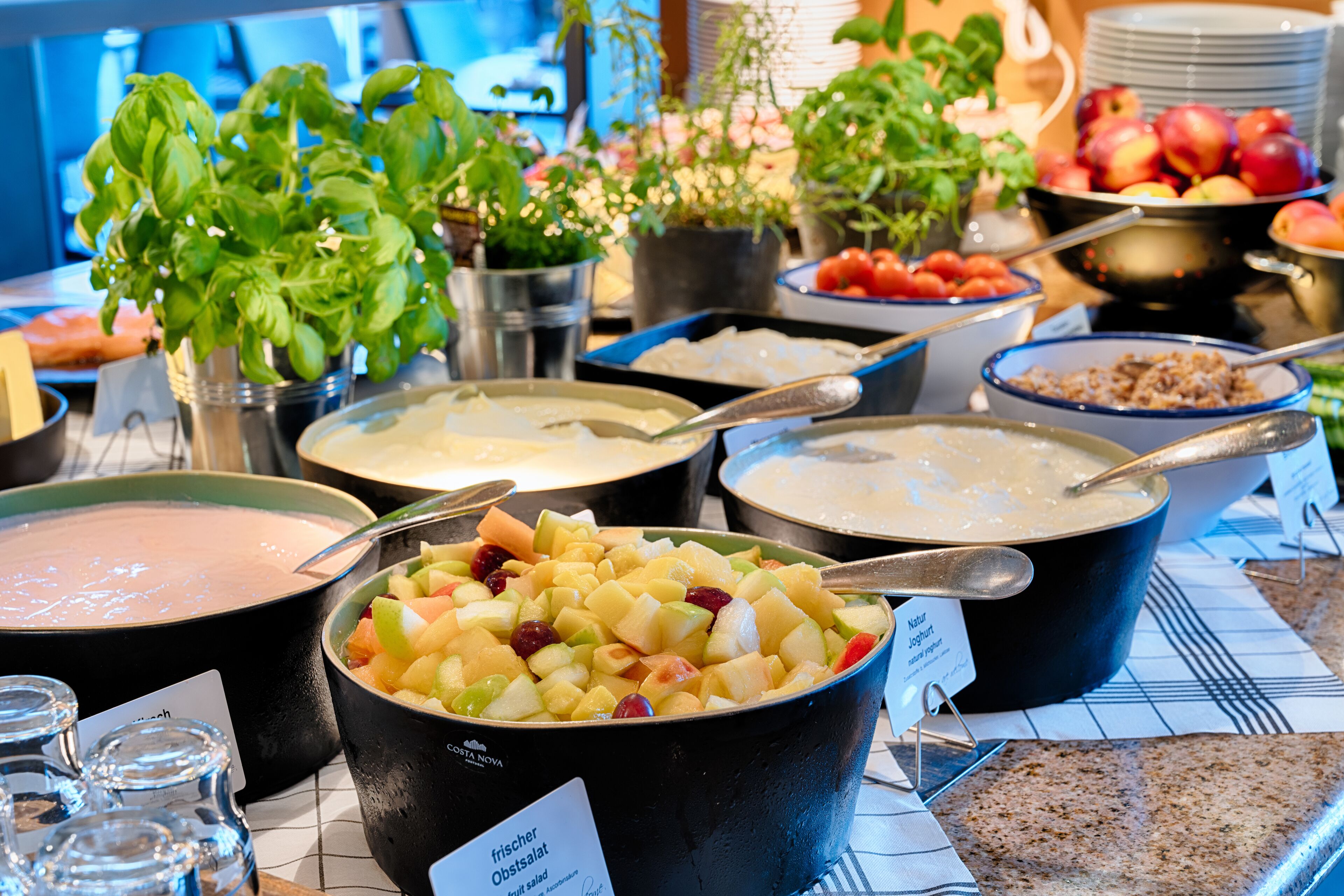 A buffet with various dishes including a fruit salad, yogurt, and other prepared foods.