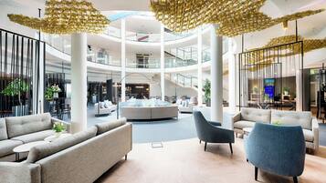 A spacious lobby with a central seating area, multiple levels, and a modern chandelier.