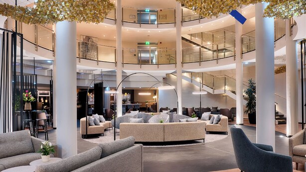 A spacious lobby with multiple seating areas, a central staircase, and a modern design. - Welcome Hotel Wesel (Wesel)