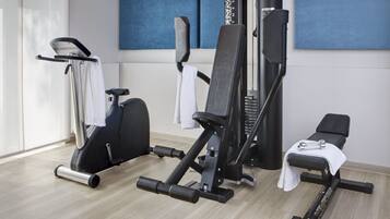 A gym with exercise equipment, a bench, and a towel rack.