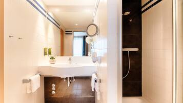 Un baño moderno con un lavamanos grande, espejo y ducha.