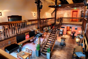 A spacious restaurant with a wooden interior, a staircase, and a bar area.