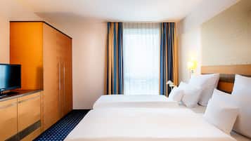 Ein Hotelzimmer mit zwei Betten, einem Fernseher und einem Kleiderschrank.