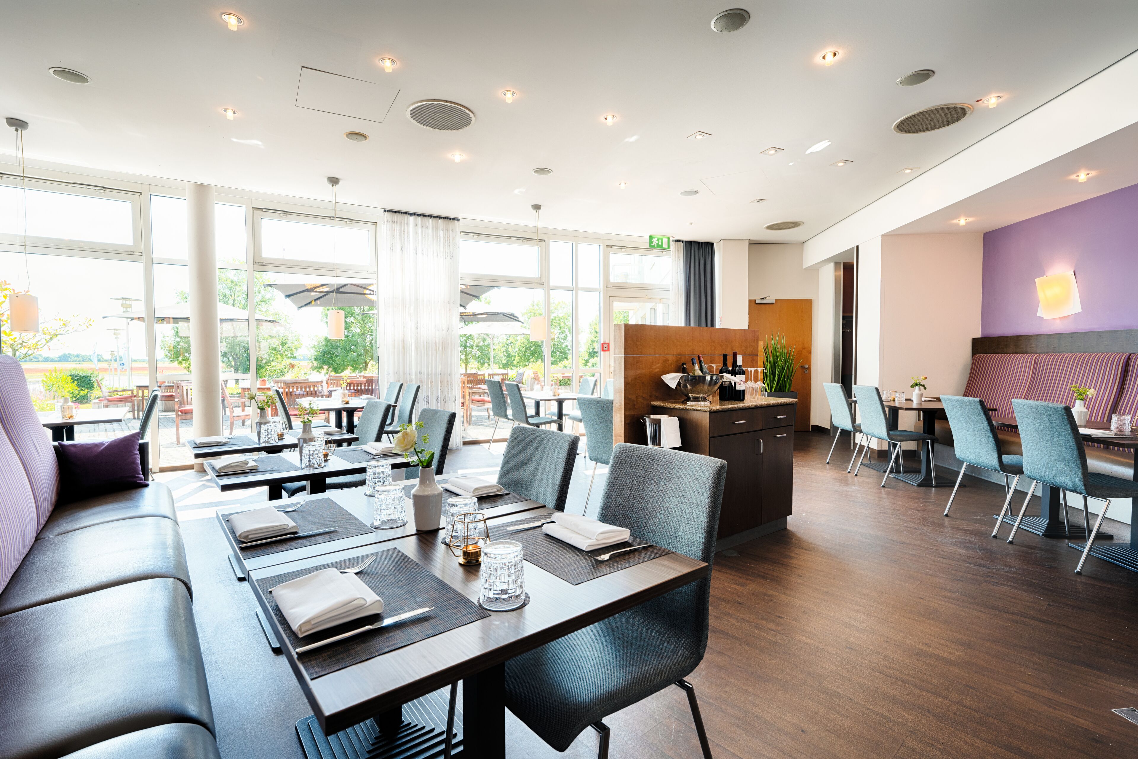 Un restaurante moderno con una larga mesa de comedor, múltiples sillas y una zona de estar con sofá.