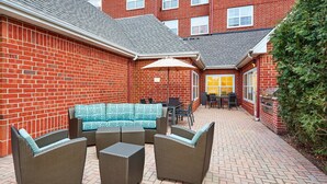 A patio area with wicker furniture, a table, and chairs.