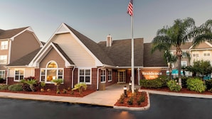 A hotel with a brick facade, a flagpole with an American flag, and a sign that reads "Residence Inn."