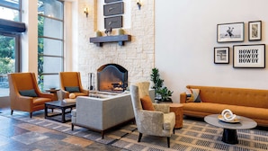 A spacious lobby with a stone fireplace, comfortable seating, and artwork on the walls.