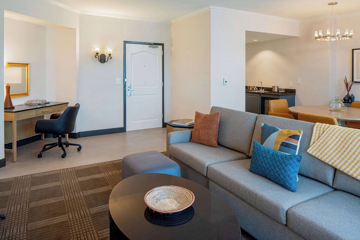 A modern living room with a gray sofa, a coffee table, and a dining area with a table and chairs.