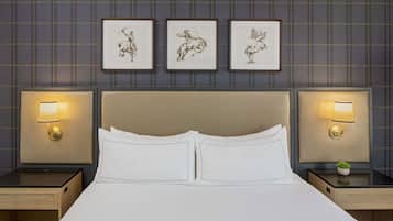 Une chambre d’hôtel avec un grand lit, deux tables de chevet avec des lampes et trois tableaux encadrés au mur.