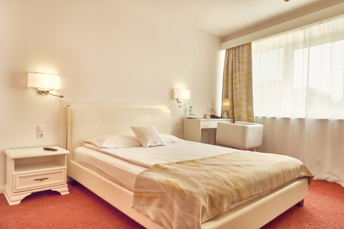 A hotel room with a bed, bedside tables, a desk, and a chair.