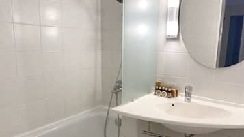 Un baño con una bañera blanca, un lavamanos blanco y un espejo.