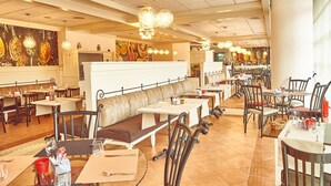 Un restaurant spacieux doté de plusieurs espaces de restauration, notamment des banquettes et des tables, ainsi que de différents types d’appareils d’éclairage.