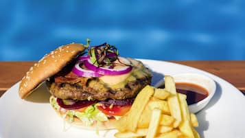 A burger with fries and a side of sauce on a white plate.