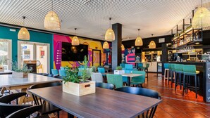 A restaurant with a modern interior, featuring a large TV screen, multiple seating areas, and a bar.