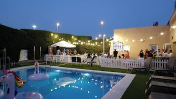 Una piscina al aire libre, sillones reclinables de piscina