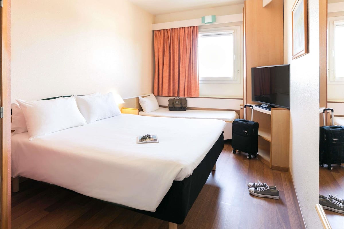 Une chambre d’hôtel avec un grand lit, une télévision, un bureau et une valise.